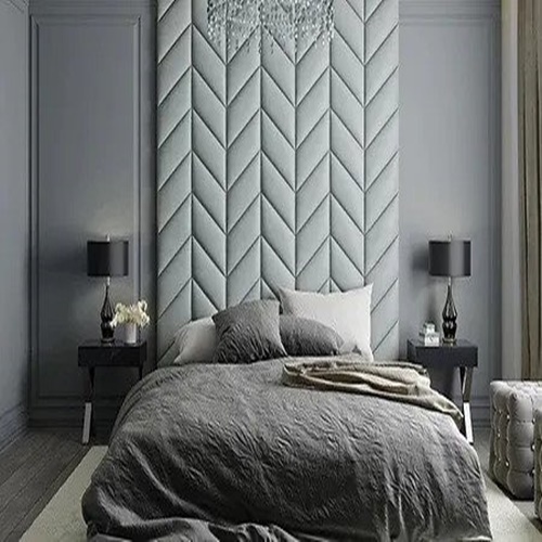 Grey wall with herringbone style upholstered wall panels behind a double bed in a luxurious hotel room